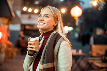 Happy pretty female ejoying hot drink outdoors