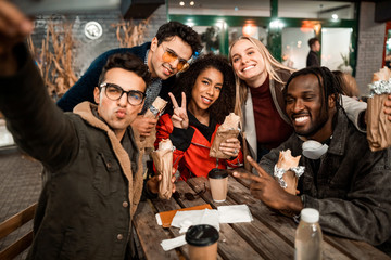 Happy young men and women posing at camera in street cafe