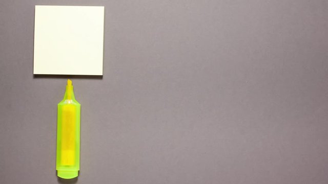 Marker, sticky note on gray background. Stop motion animation flat lay top view. Education and back to school concept.