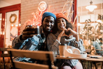 Fototapeta na wymiar Happy Afro American guy sitting near girlfriend in street cafe