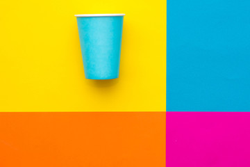 Blue paper disposable cup on beautiful multicolored background. Top view. Minimalist Style. Copy, empty space for text