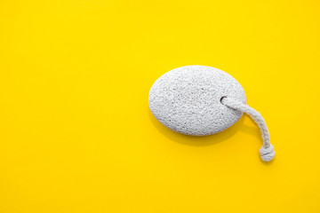 Natural pumice stone with white rope on yellow background. Pedicure and spa concept. Pumice stone...