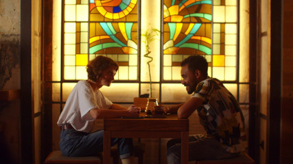 Couple sit at a table in a cafe, talk with smile and drink tea