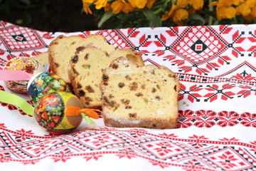 Painted Easter eggs, slices of Easter cake on an embroidered napkin - traditional Easter breakfast, decorated in rustic style, selective focus