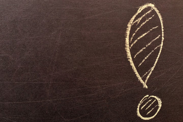 Bright yellow exclamation mark drawn in chalk on a school brown noisy blackboard. Symbolizes statement and contains copyspace