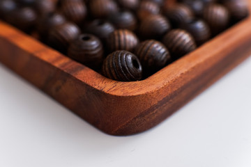 brown beads on a wooden tray and a white table