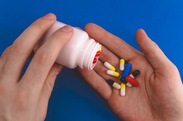man pours pills in his hand on a blue background
