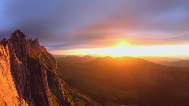 FPV aerial view over the Alpstein ridge, in the Appenzell Alps, revealing dark clouds and the sunset, on a moody summer evening, in Switzerland