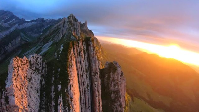 FPV aerial view over the Appenzell Alps, revealing a man standing on the Schaefler Ridge, at sunset, on a sunny summer evening, in Switzerland