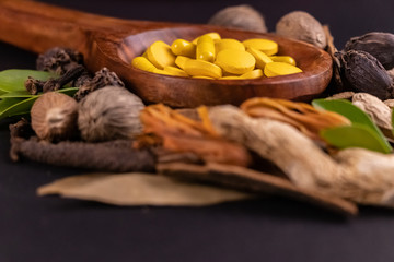 Ayurvedic medicine concept. Close-up view of yellow herbal drugs in a wooden spoon on black background