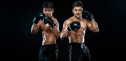 Boxers. Two male fighters in boxing gloves in combat racks on a black background. Fitness concept....