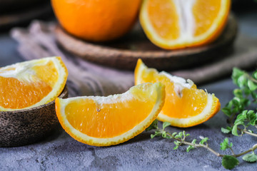 Photo of fresh orange on retro background. A slice of orange with green leaves. Half of orange on wooden plate bowl. Free space for text. Dark background. Image