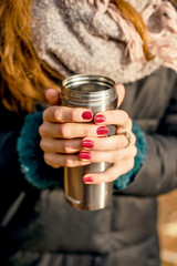 Cup of hot drink is holding by hands 