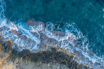 Waves beat against a rocky shore, aerial view