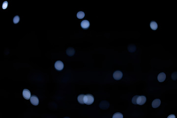 Silver and blue lights of the festive city on black background.