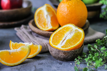 Photo of fresh orange on retro background. A slice of orange with green leaves. Half of orange on wooden plate bowl. Free space for text. Dark background. Image