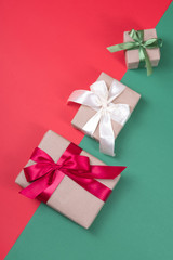 Beautiful packaging of presents with satin ribbons, craft paper on red and green background.