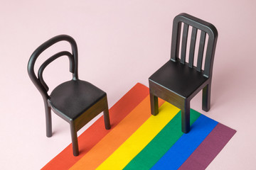 Small chairs on lgbt pride parade flag abstract on pastel pink background.