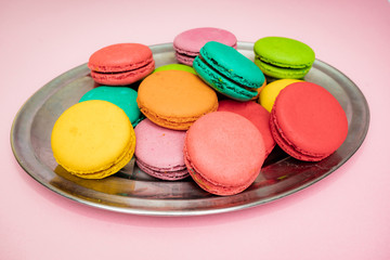 A lot of french colorful macarons on a pink background