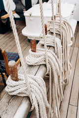 Old sailboat, closeup of wooden cleats with nautical moored ropes.