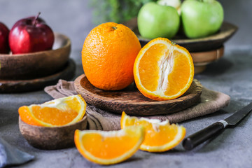 Photo of fresh orange on retro background. Slice of orange in front of fruits and vegetables. Half of the orange on wooden plate bowl. Sunkist. Summer. Image