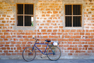 Fototapeta na wymiar Blue mountain bike parked leaning against a brick wall with two windows