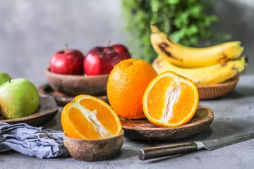 Photo of fresh orange on retro background. Slice of orange in front of fruits and vegetables. Half of the orange on wooden plate bowl. Sunkist. Summer. Image