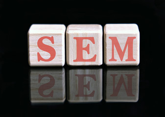 SEM text on wooden cubes on a monochrome background with reflection.