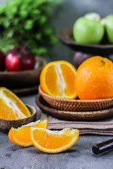 Photo of fresh orange on retro background. Slice of orange in front of fruits and vegetables. Half of the orange on wooden plate bowl. Sunkist. Summer. Image