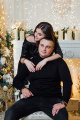 Loving couple, is stylishly dressed near a Christmas tree. Christmas time. Christmas mood. Loving couple celebrating New Year and Christmas. A guy with a girl pose in a studio