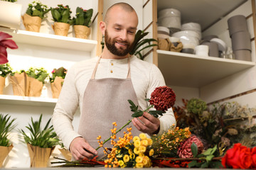 Florist making bouquet with fresh flowers at table in shop