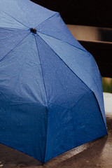 Rain drops on open umbrella, blue color, umbrella on the ground.