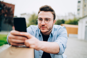 Calm male surfing phone in street