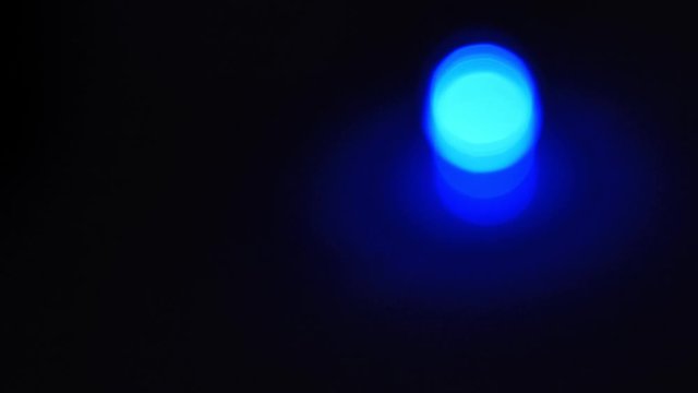 The blue garland diode slowly lights up and fades out. The light bulb is out of focus. Flank. The background is a gradient. Christmas, new year, technology. 4K.