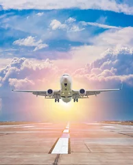 Zelfklevend Fotobehang Witte passagiersvliegtuigen stijgen op vanaf de startbaan van de luchthaven tegen de achtergrond van een schilderachtige avondlucht met zonnestralen © Dushlik
