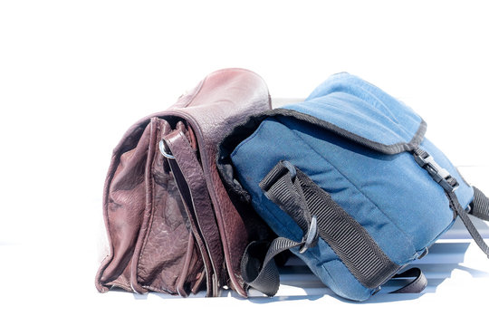 A Brown Leather Satchel And A Blue Canvas Camera Bag Against A White Background.