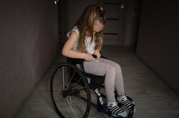 Beautiful sad girl child disabled child sitting in a wheelchair. Victims of a car accident. Disabled children concept