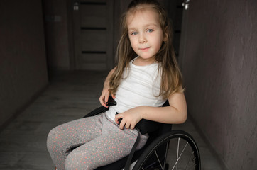 Beautiful sad girl child disabled child sitting in a wheelchair. Victims of a car accident. Disabled children concept
