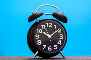 Bell Clock black color on wood with blue background,copyspace