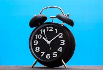 Bell Clock black color on wood with blue background,copyspace