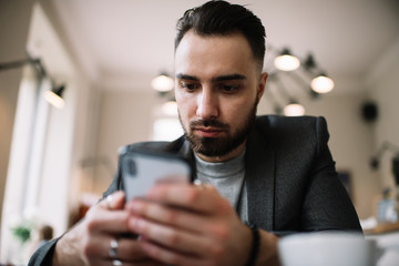 Man chatting on smartphone in cafe