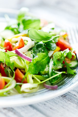 Healthy salad with rocket, cherry tomatoes, cucumber, red onion and fresh herbs. Close up. 