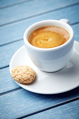 Cup of coffee with amaretti (Italian biscuit) on bright wooden background. Close up.