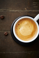 Cup of coffee on brown background. Close up. Top view. 