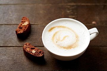 Cup of coffee with cantuccini (Italian cookies) on rustic wooden background.
