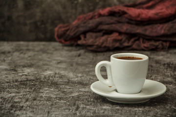 White cup with black coffee and grains of coffee on a background of gray stone. View from above. Place for text.