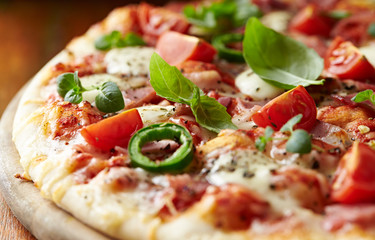 Pizza with ham, cherry tomatoes, mozzarella cheese, jalapeno pepper and fresh herbs. Close up.