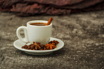 White cup with black coffee and grains of coffee on a background of gray stone. View from above. Place for text.