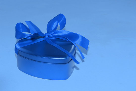 Christmas gift box with ribbon on a blue background, free space for text - holidays, winter and holiday concept - tinted trendy classic blue 2020