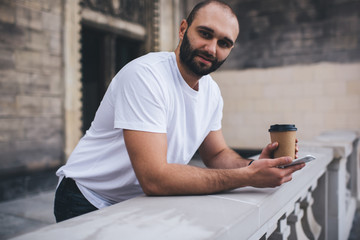 Bearded man leaning on fence browsing smartphone